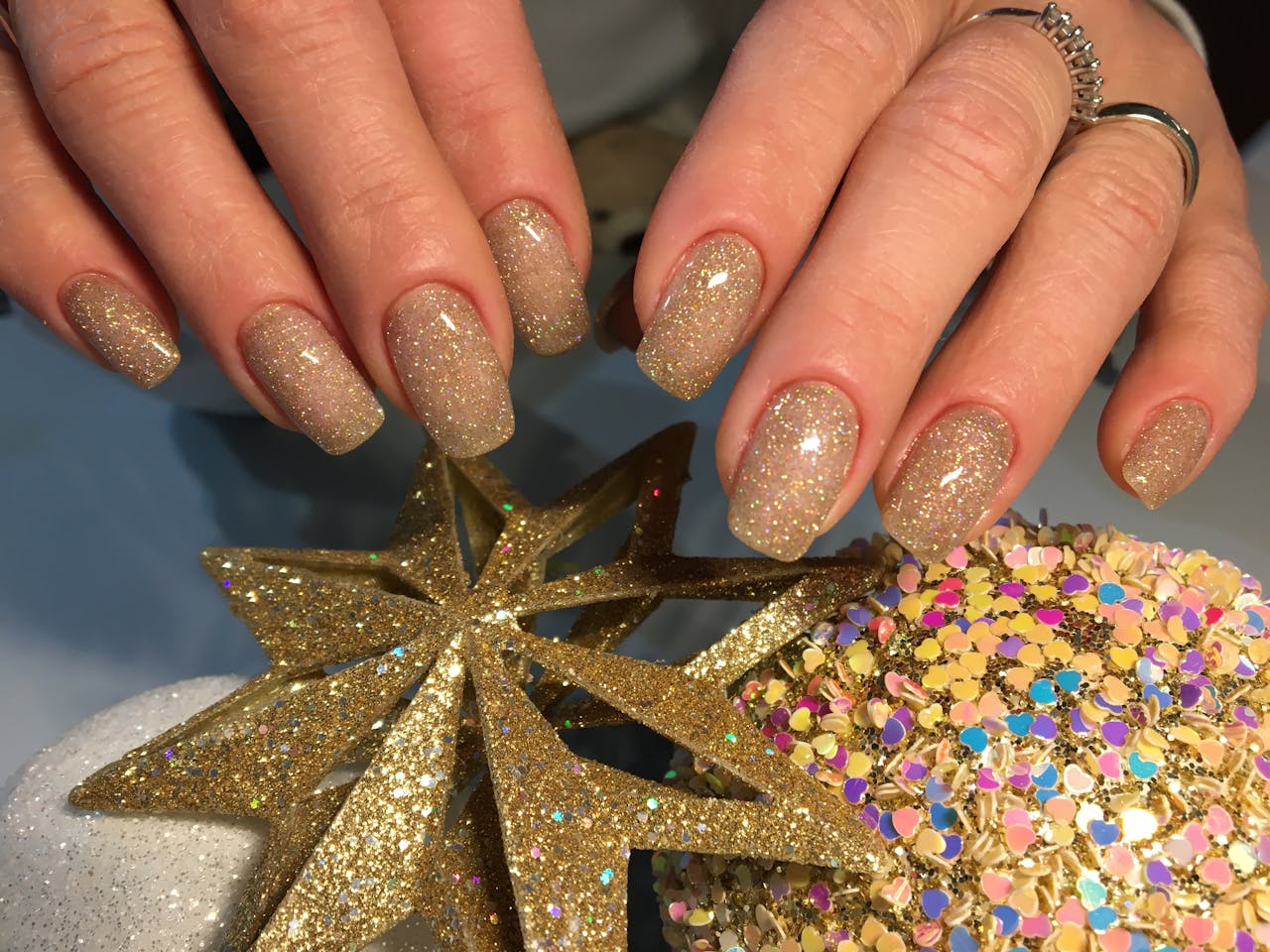 Elegant gold-glittered nails with star decorations, perfect for festive occasions.