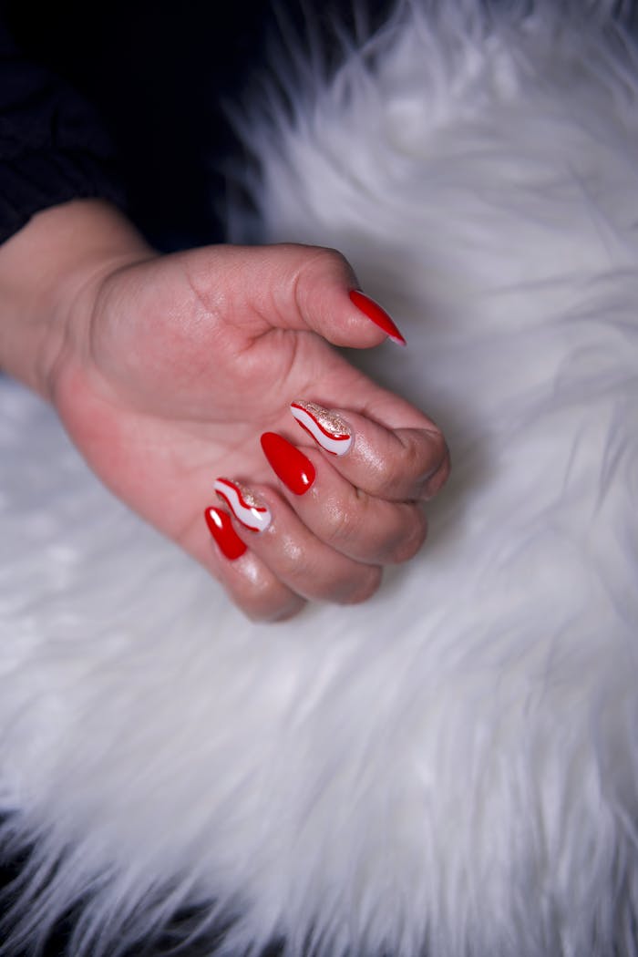 Stylish red manicure with artistic patterns on a soft white faux fur background.