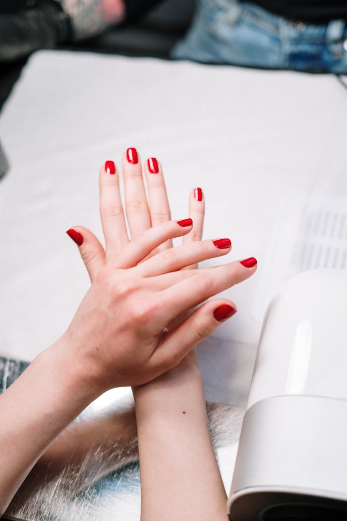 Close-up of red manicured nails during a salon session with nail tools.
